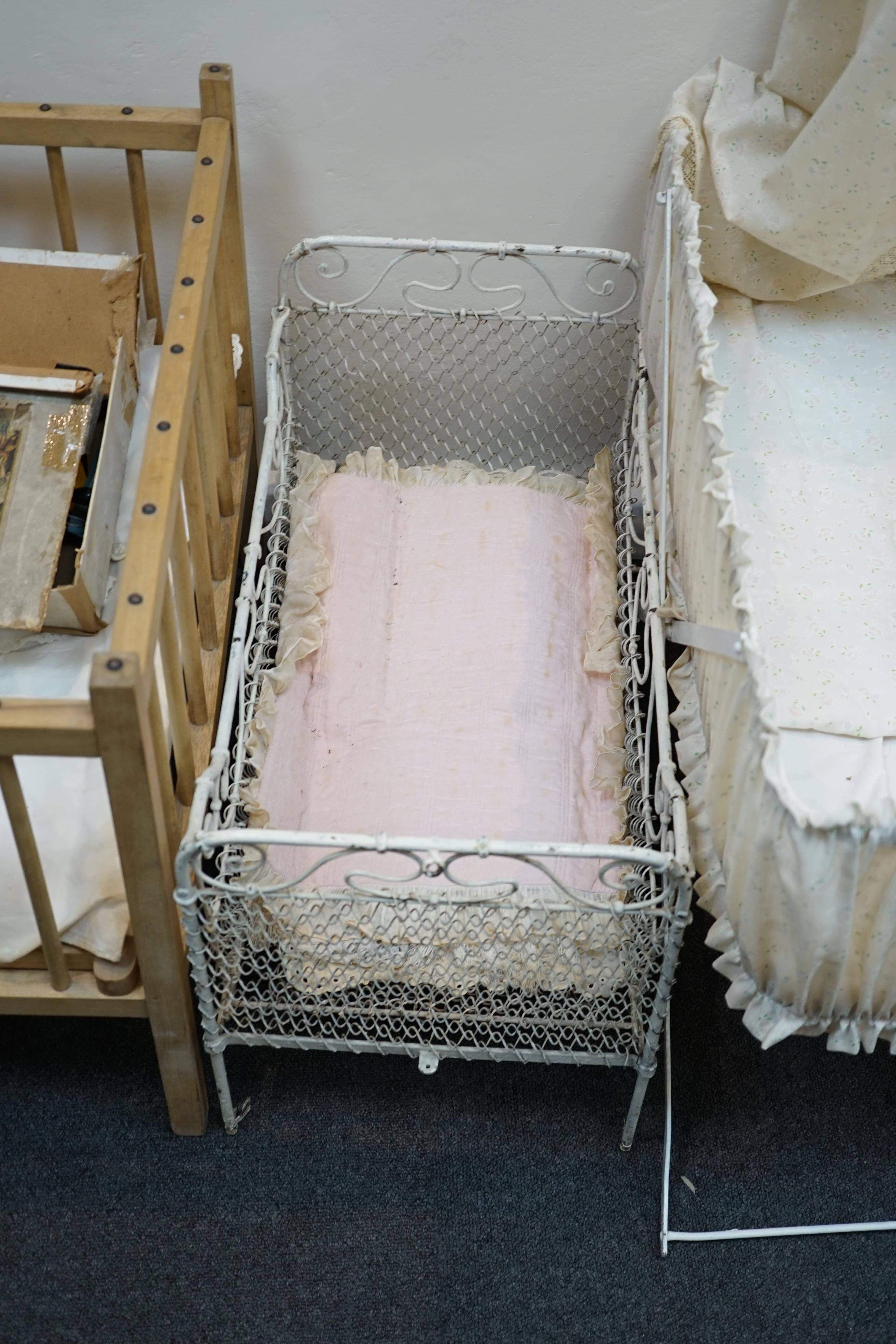 A collection of nine doll’s cribs of wood or wrought iron construction, together with two nineteenth century style doll’s ’bath chairs’, a toy mangle, Disney themed Snow White carpet sweeper and a boxed child’s sewing ma